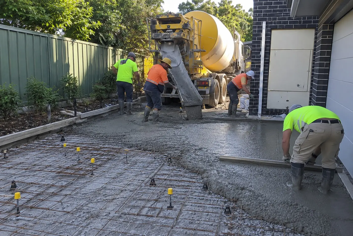 Concrete truck and crew pouring a replacement driveway section