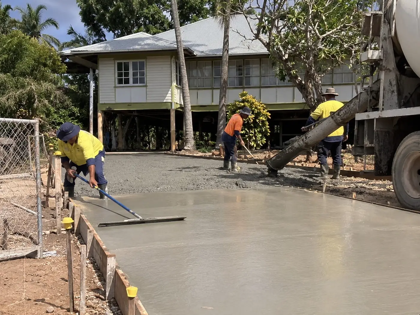 Concreters screeding a fresh pour as concrete runs from the truck chute