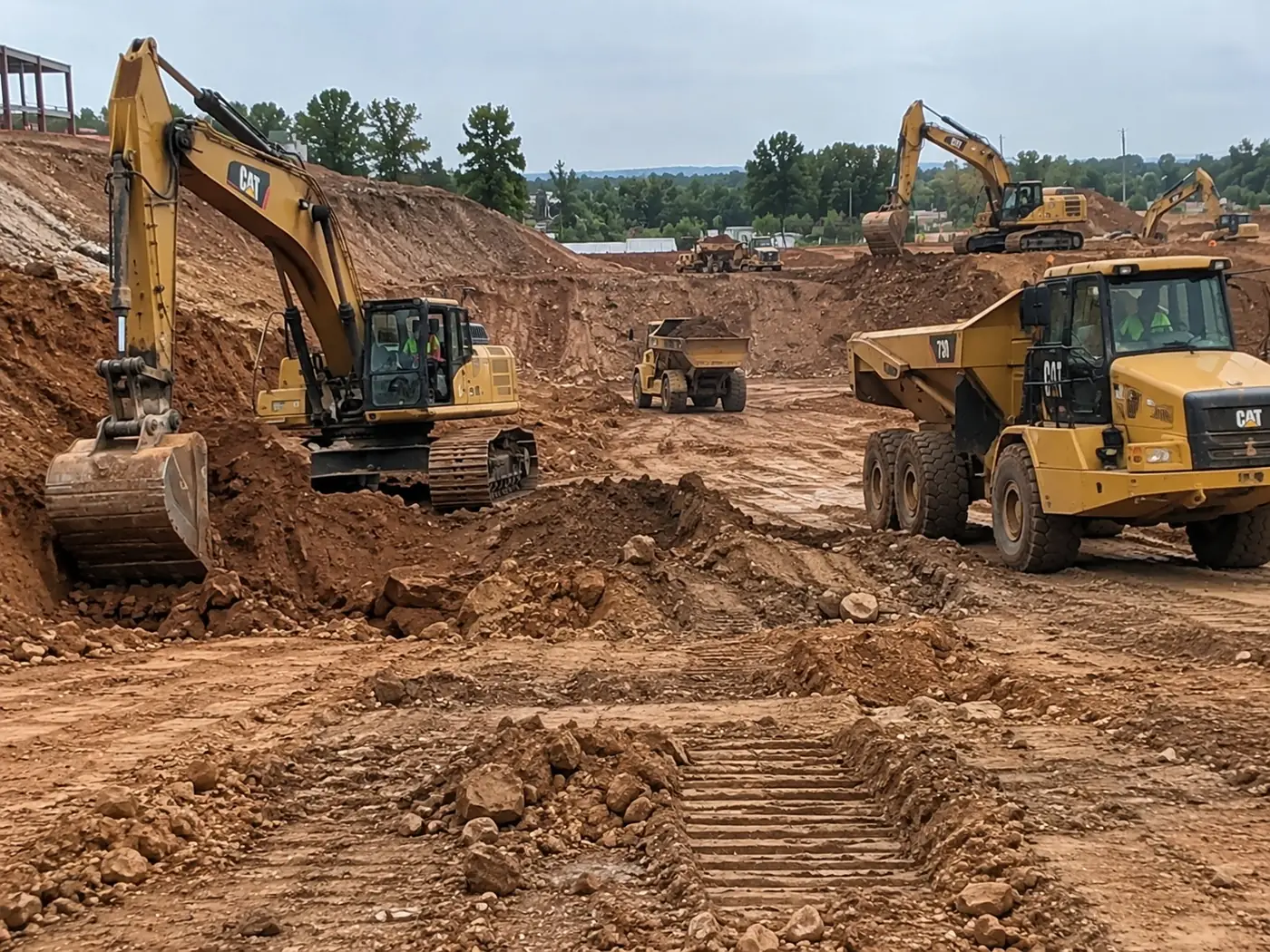Excavator digging beside an articulated dump truck on an earthworks site